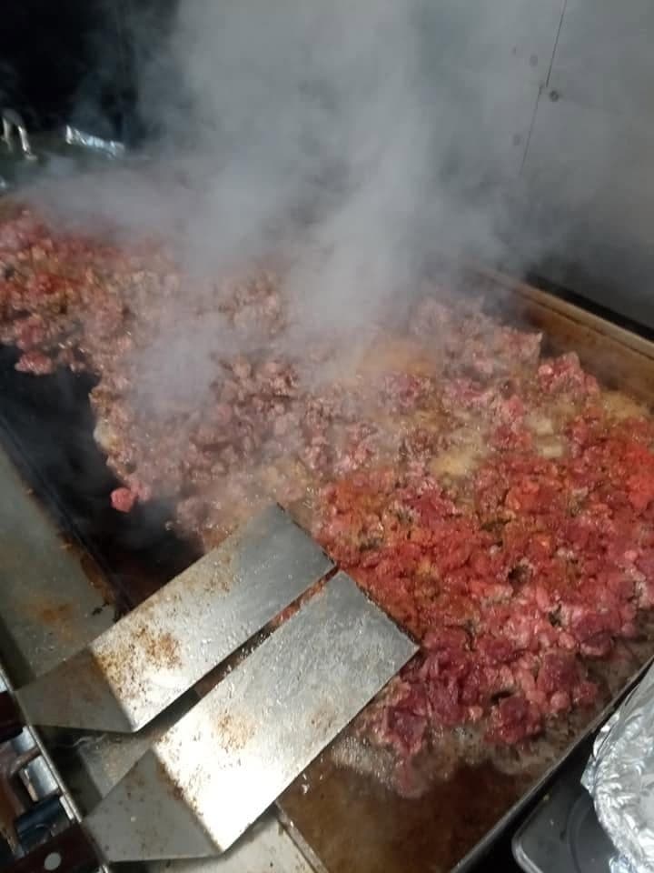 Marinated al pastor meat cooking on the griddle, made fresh to order at Juanito’s Tacos