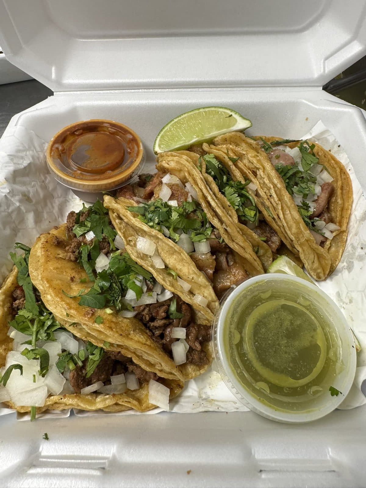 A plate of asada street tacos with green salsa and lime at Juanito’s Tacos in Urbana