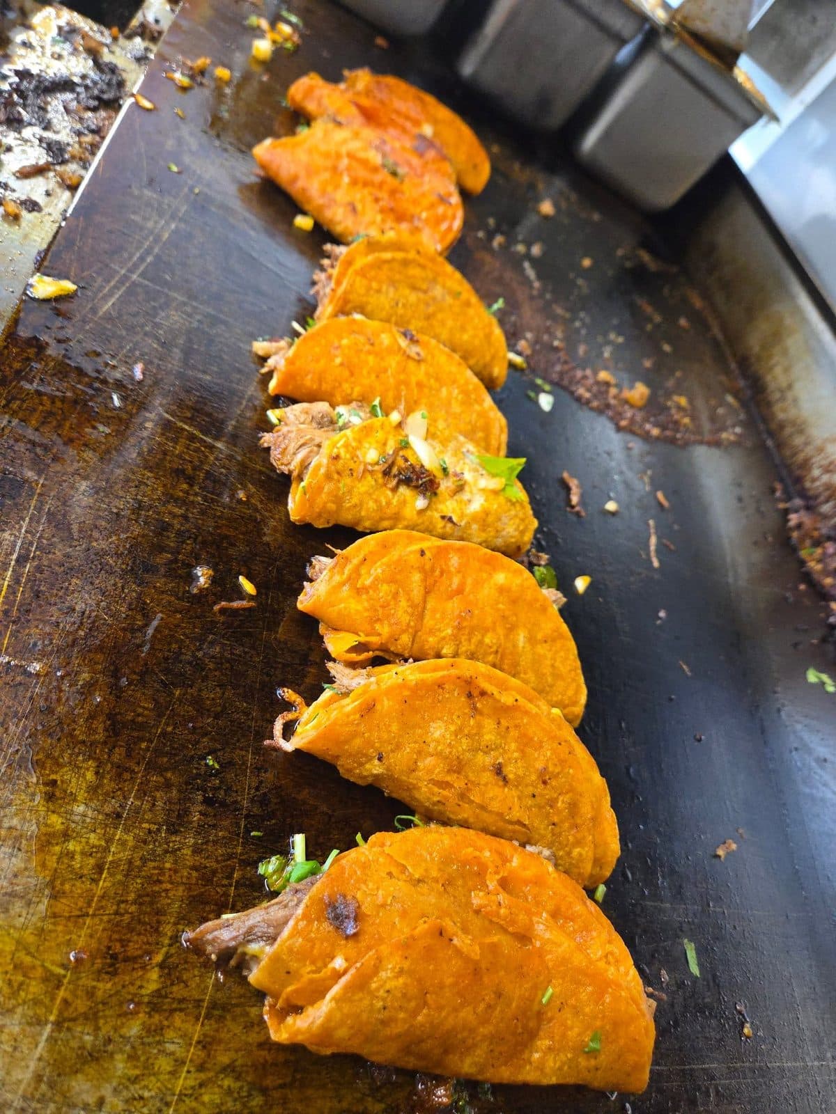 Cheese quesadillas crisping on the flat-top griddle at the Juanito’s Tacos stand
