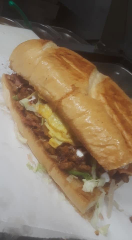 Torta cubana piled high with meat and fresh toppings on telera bread at Juanito’s Tacos